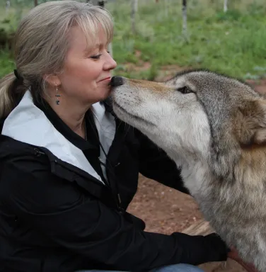 Beth and Kekoa face to face woman and grey wolf dog face to face