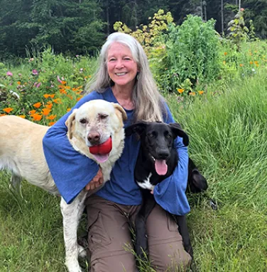 Elizabeth with her two dogs, Wilber and Pretzel white haired woman with two dogs in a field