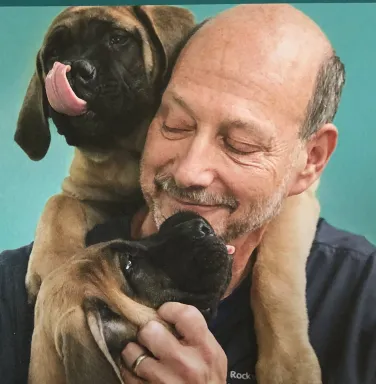 Dr. Wolchinsky with 2 brown puppies smiling man with 2 brown puppies